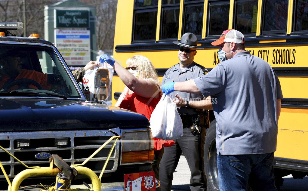 Warren Dillaway Ohio State Highway Patrol Sgt. Larry Johnson, back center, assists Ashtabula Area City Schools employees Tina McCoy, left, and John Peterson, far right, at a meal delivery site along Route 20 in Ashtabula, Ohio, on Thursday April 2, 2020, morning. (Warren Dillaway/The Star-Beacon via AP)