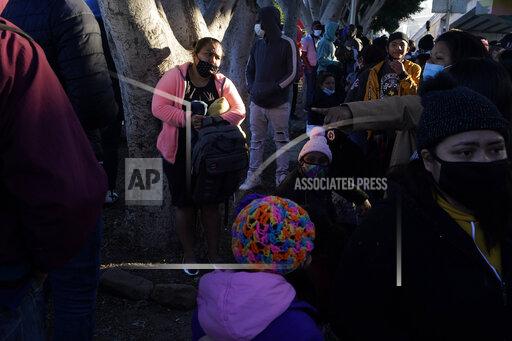 FILE - A woman seeking asylum in the United States waits with others for news of policy changes on Feb. 19, 2021, in Tijuana, Mexico. The Biden administration is set to reinstate a Trump-era policy to make asylum-seekers wait in Mexico for hearings in U.S. immigration court this week with changes and additions. A U.S. official says the first migrants are to be sent from El Paso, Texas, back to Ciudad Juarez. Timing was in flux as officials made final preparations but it may begin Tuesday, Dec. 7, 2021. (AP Photo/Gregory Bull, File)