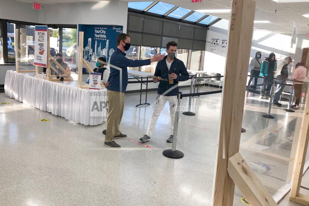 An election official directs Jason Miller of Minneapolis to the check-in desk at the city's early voting center on Friday, Sept. 18, 2020. Miller was the first in line at the center in Minneapolis as early voting opened in Minnesota. (AP Photo/Steve Karnowski)