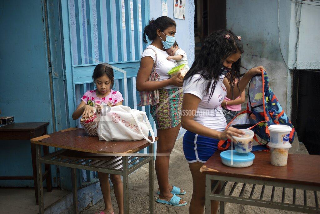 Ariana Cubillos Children put donated food into their backpacks at the San Antonio de Padua soup kitchen in the Petare neighborhood of Caracas, Venezuela, Thursday, June 10, 2021, amid the new coronavirus pandemic. (AP Photo/Ariana Cubillos)