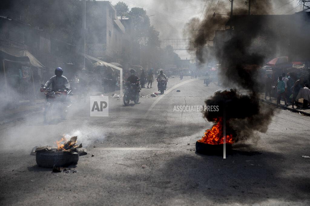 Rodrigo Abd Motorcycles ride past a barricade of burning tires during a protest by residents over a police raid that resulted in the death of a young musician, in downtown Port-au-Prince, Haiti, Wednesday, Sept. 22, 2021. Violence can breakout at any time, in any random corner of the city. Angry mobs gather and dissolve, reunite and prepare for a new confrontation, while bystanders await the unexpected. (AP Photo/Rodrigo Abd)