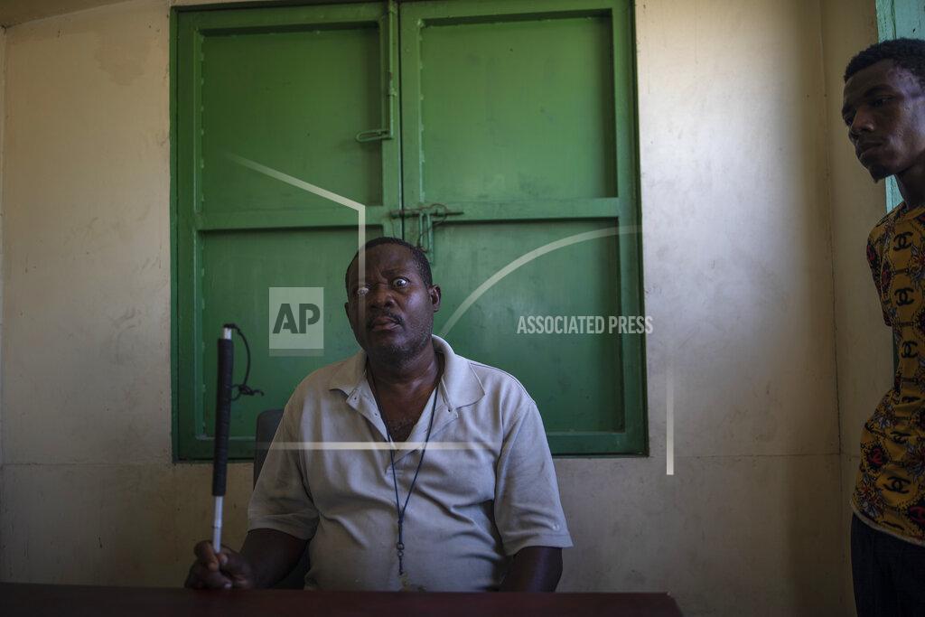 Rodrigo Abd Leader La Piste's displaced residents, Joseph Dieu Faite, who is visually impaired, recalls the assault lead by police in June, at a shelter for the internally displaced in Port-au-Prince, Haiti, Friday, Sept. 17, 2021. "There were some gangsters there, I have to acknowledge that, but the police did not ask, did not say a word, did not make a difference, just evicted us and then took matches and gasoline and burned our houses one by one," Faite said. (AP Photo/Rodrigo Abd)