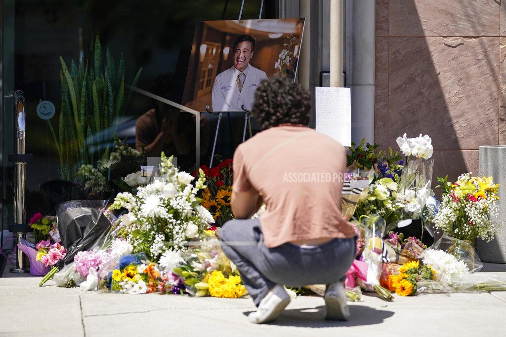 Ashley Landis Gabe Kipers, a neighbor of Dr. John Cheng, kneels at a memorial for him outside his office building on Tuesday, May 17, 2022, in Aliso Viejo, Calif. Cheng, 52, was killed in Sunday's shooting at Geneva Presbyterian Church. (AP Photo/Ashley Landis)