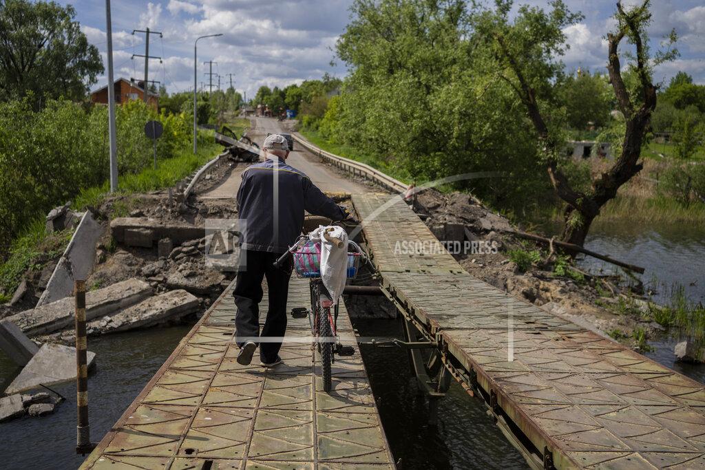 Bernat Armangue A man pushes his bicycle across a repaired bridge in Vilkhivka, outside Kharkiv, in eastern Ukraine, Friday, May 20, 2022. (AP Photo/Bernat Armangue)