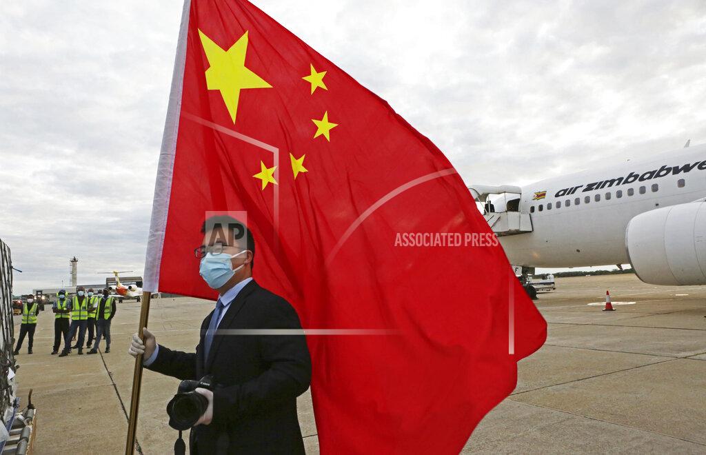 Tsvangirayi Mukwazhi FILE - In this Monday, Feb, 15, 2021 file photo, an official from the Chinese embassy in Zimbabwe holds a Chinese flag next to a plane carrying Sinopharm COVID-19 vaccine from China upon arrival at Robert Mugabe International Airport in Harare. Zimbabwe received its first COVID-19 vaccines with the jet carrying 200,000 Sinopharm doses from China. (AP Photo/Tsvangirayi Mukwazhi)