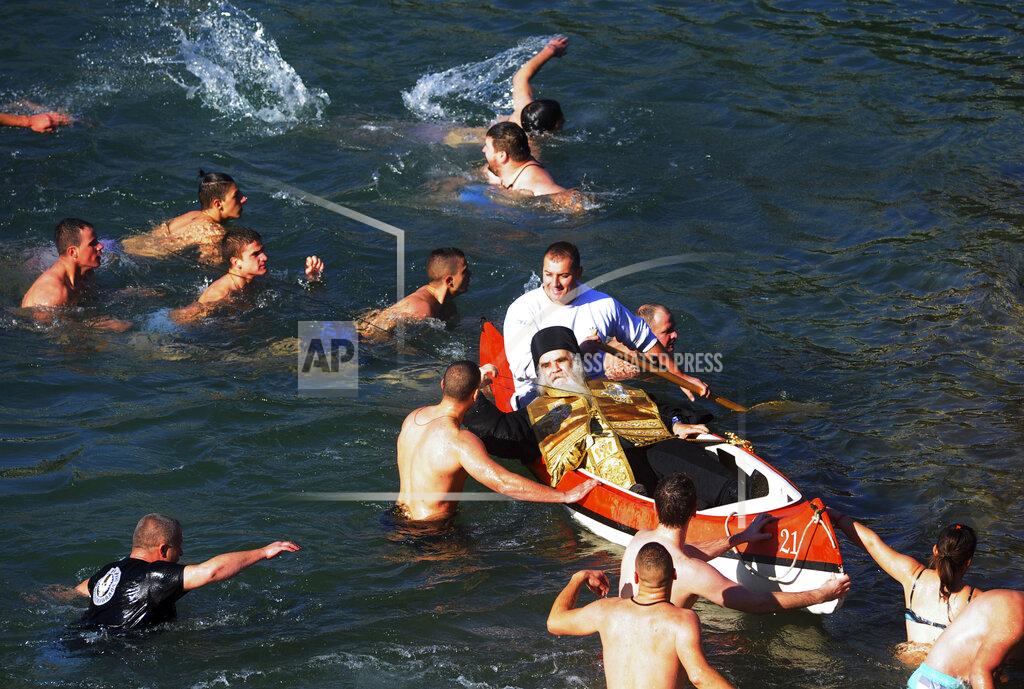 Risto Bozovic FILE - In this Jan. 19, 2016 file photo, Bishop Amfilohije ducks down as he rides in a canoe, while swimmers participate in a traditional cross retrieval race in the river Ribnica, marking Orthodox Epiphany, in Podgorica, Montenegro. Amfilohije, the head of the Serbian Orthodox Church in Montenegro, which led months of protests against the small Balkan state's pro-Western government, has died in hospital after contracting the coronavirus, the church said Friday, Oct. 30, 2020. (AP Photo/Risto Bozovic, File)