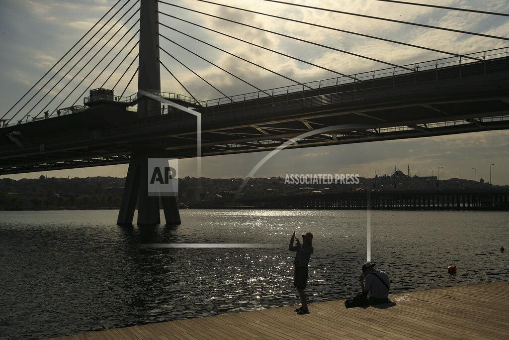 Emrah Gurel A woman takes a picture by the Golden Horn, leading to the Bosphorus Strait separating Europe and Asia, in Istanbul, Friday, May 14, 2021.Turkey is in the final days of a full coronavirus lockdown and the government has ordered people to stay home and businesses to close amid a huge surge in new daily infections. But millions of workers are exempt and so are foreign tourists. Turkey is courting international tourists during an economic downturn and needs the foreign currencies that tourism brings to help the economy as the Turkish lira continues to sink. (AP Photo/Emrah Gurel)