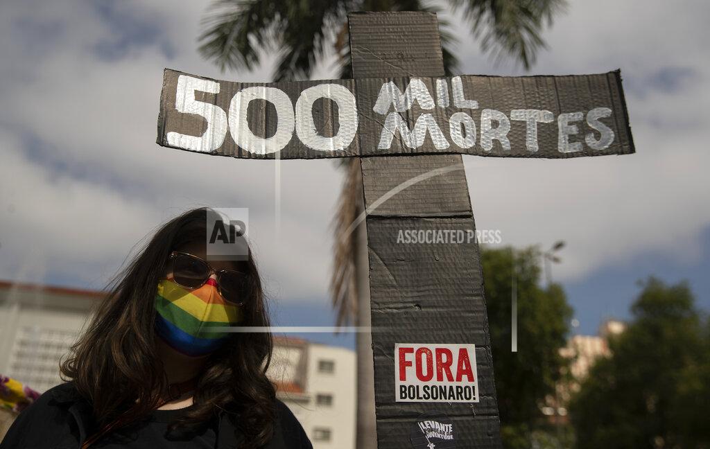 Andre Penner A woman, wearing a protective face mask, holds a sign in the shape of a cross with a message that reads in Portuguese;"500 k deaths", during a protest against Brazilian President Jair Bolsonaro and his handling of the pandemic and economic policies protesters say harm the interests of the poor and working class, in Cuiaba, Brazil, Saturday, June 19, 2021. Brazil is approaching an official COVID-19 death toll of 500,000 — second-highest in the world. (AP Photo/Andre Penner)