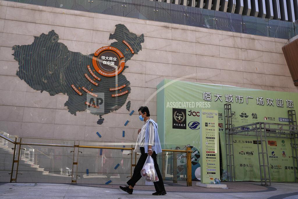 Andy Wong A woman wearing a face mask to help protect herself from the coronavirus walks by a map showing Evergrande development projects in China, at an Evergrande city plaza in Beijing, Tuesday, Sept. 21, 2021. Global investors are watching nervously as the Evergrande Group, one of China's biggest real estate developers, struggles to avoid defaulting on tens of billions of dollars of debt, fueling fears of possible wider shock waves for the Chinese financial system. (AP Photo/Andy Wong)