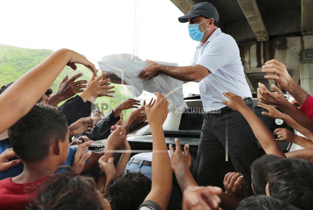 Delmer Martinez A person distributes food to hurricane victims under a bridge in San Pedro Sula, Honduras, Saturday, Nov. 21, 2020. Shelters for people whose homes were flooded or damaged by hurricanes Eta and Iota in Honduras are now so crowded that thousands of victims have taken refuge under highway overpasses or bridges. The Red Cross estimates that about 4.2 million people were affected by the back-to-back hurricanes in November in Honduras, Nicaragua and Guatemala. (AP Photo/Delmer Martinez)
