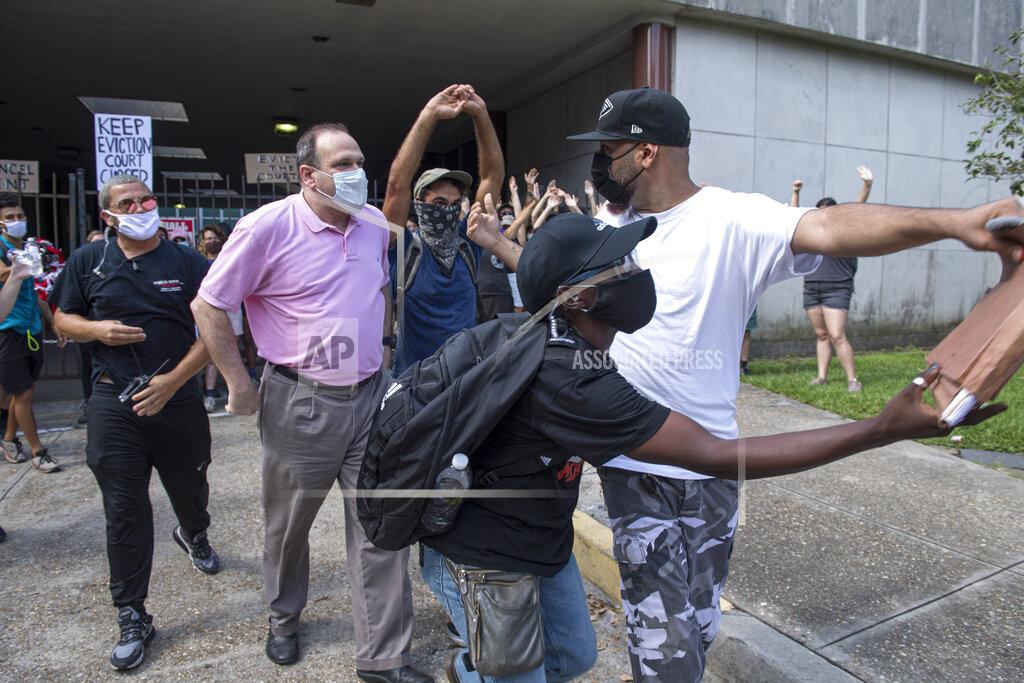 Chris Granger A protester, right, walks away with paperwork after grabbing it out of the hands of a man, left center, who was trying to enter First City Court while the New Orleans Renters Rights Assembly protest was taking place outside First City Court near New Orleans City Hall on Thursday, July 30, 2020. Other protesters intervened and returned the paperwork to the man. (Chris Granger/The Advocate via AP)