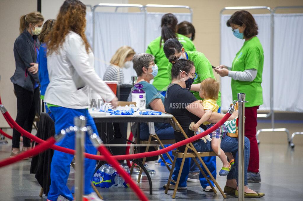 Chris Granger Staff of Ochsner Health gather around a table to administer the Johnson & Johnson COVID-19 vaccine at the Castine Center in Pelican Park in Mandeville, La., on Wednesday, March 10, 2021. (Chris Granger /The Advocate via AP)