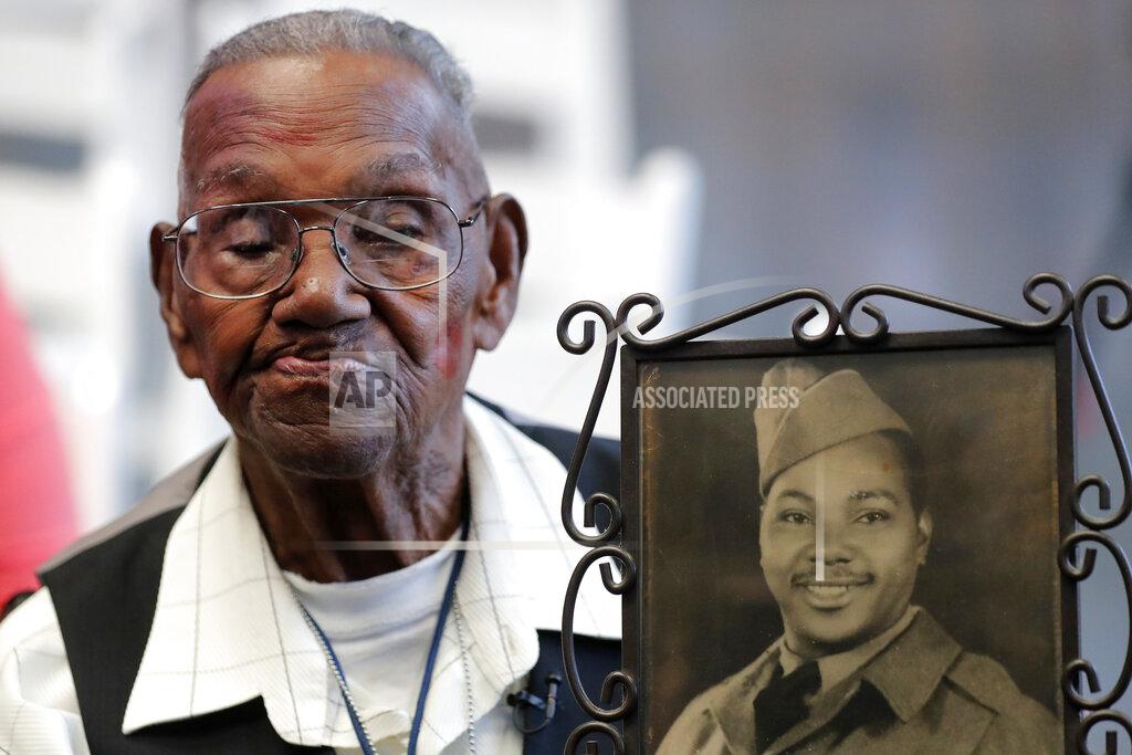 Gerald Herbert FILE - In this Sept. 12, 2019 file photo, World War II veteran Lawrence Brooks holds a photo of him taken in 1943, as he celebrates his 110th birthday at the National World War II Museum in New Orleans. Brooks celebrated his 112th birthday, Sunday, Sept. 12, 2021 with a drive-by party at his New Orleans home hosted by the National War War II Museum. Drafted in 1940, Brooks was a private in the Army’s mostly Black 91st Engineer Battalion. (AP Photo/Gerald Herbert, File)