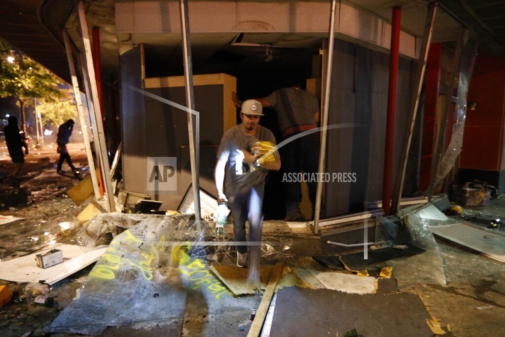 John Minchillo A person takes items from a liquor store Thursday, May 28, 2020, in Minneapolis. Protests over the death of George Floyd, a black man who died in police custody Monday, broke out in Minneapolis for a third straight night. (AP Photo/John Minchillo)