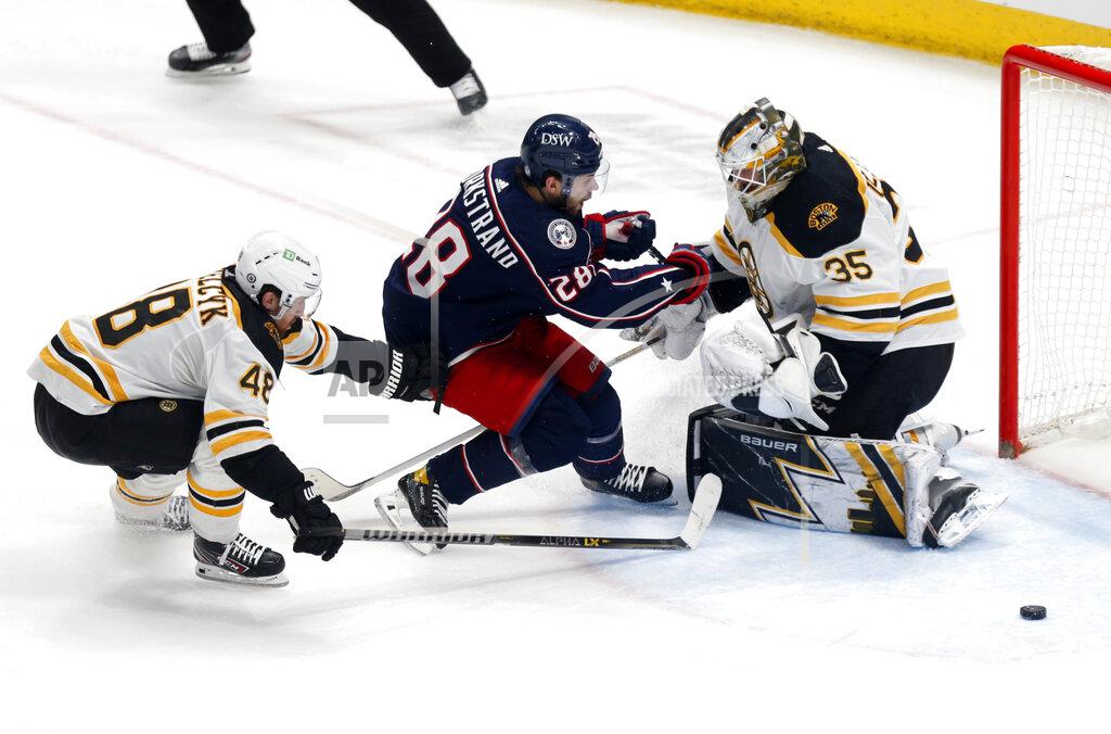 Paul Vernon Boston Bruins goalie Linus Ullmark, right, stops a shot by Columbus Blue Jackets forward Oliver Bjorkstrand in front of Bruins defenseman Matt Grzelcyk during the third period of an NHL hockey game in Columbus, Ohio, Monday, April 4, 2022. (AP Photo/Paul Vernon)