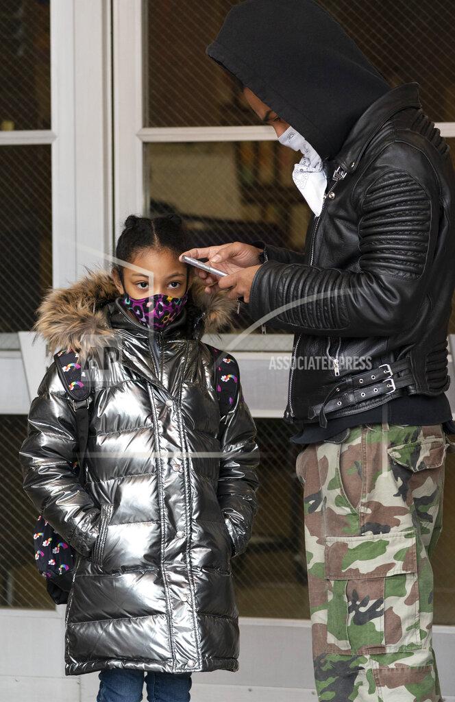 Mark Lennihan Dante Kneece and his step-daughter Marciella wait for P.S. 134 Henrietta Szold Elementary School to open, Monday, Dec. 7, 2020, in New York. Public schools reopened for in-school learning Monday after being closed since mid-November. (AP Photo/Mark Lennihan)