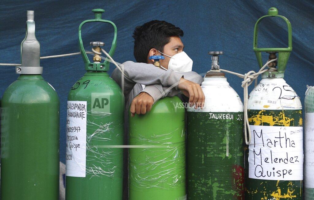 Martin Mejia A youth rests on his empty oxygen cylinder waiting for a refill shop to open in the San Juan de Lurigancho neighborhood of Lima, Peru, Monday, Feb. 22, 2021. A crisis over the supply of medical oxygen for coronavirus patients has struck in Africa and Latin America, where warnings went unheeded at the start of the pandemic and doctors say the shortage has led to unnecessary deaths. (AP Photo/Martin Mejia)