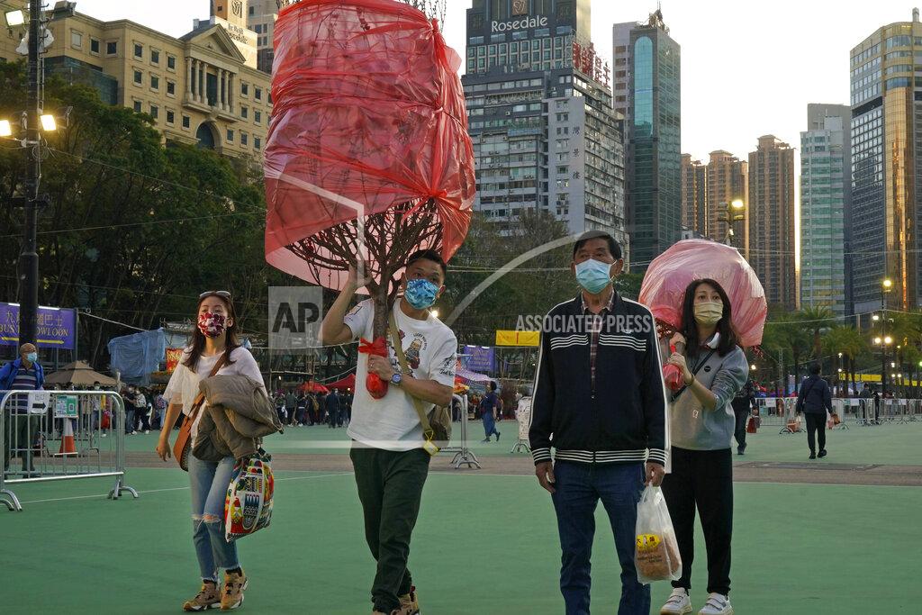 Kin Cheung Customers wearing face masks to protect against the spread of the coronavirus, carry peach blossom trees at the flower markets in Victoria Park of Hong Kong, Saturday, Feb. 6, 2021. Traditional Lunar New Year flower markets opened Saturday in Hong Kong, after a government virus policy U-turn. At the biggest venue, Victoria Park next to the popular downtown shopping district of Causeway Bay, the eerie emptiness is in stark contrast to the usual bustle of capacity crowds.(AP Photo/Kin Cheung)