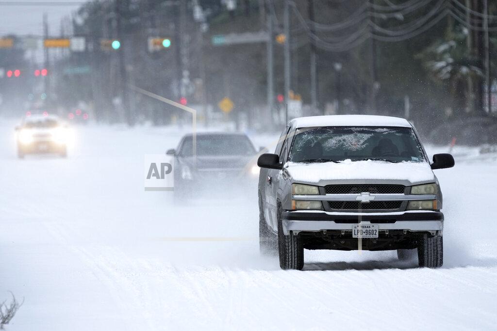 David J. Phillip Vehicles drive on snow and sleet covered roads Monday, Feb. 15, 2021, in Spring, Texas. A winter storm dropping snow and ice sent temperatures plunging across the southern Plains, prompting a power emergency in Texas a day after conditions canceled flights and impacted traffic across large swaths of the U.S. (AP Photo/David J. Phillip)