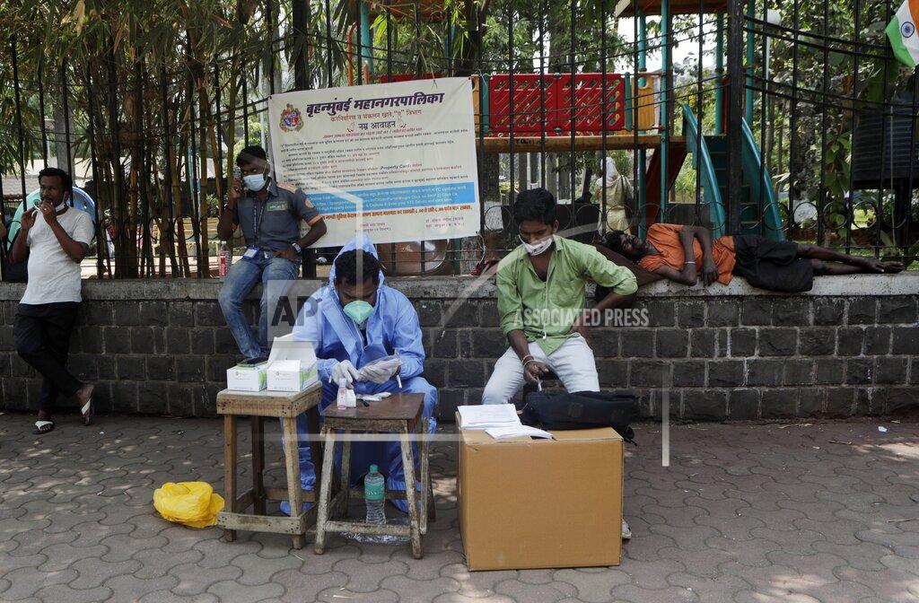 Rajanish Kakade A health workers waits to conduct tests for COVID-19 at a roadside camp in Mumbai, India, Thursday, March 25, 2021. (AP Photo/Rajanish Kakade)