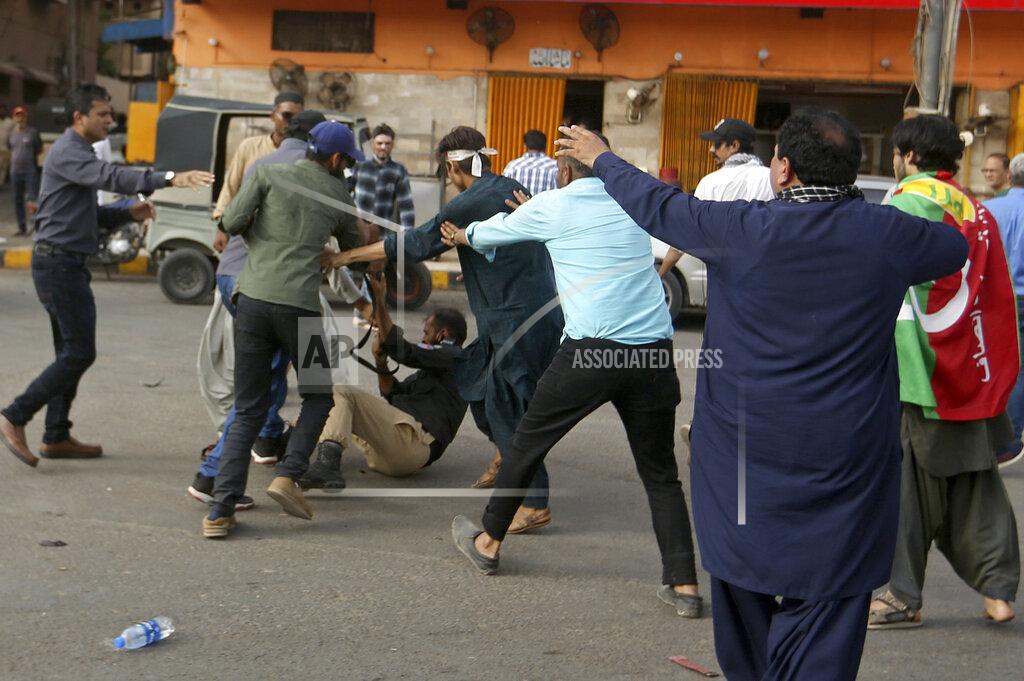 Fareed Khan Supporters of Pakistan's key opposition party scuffle with a police officer knocked to the ground during an anti-government rally, in Karachi, Pakistan, Wednesday, May 25, 2022. Pakistani police have fired tear gas and scuffled with stone-throwing supporters of defiant former Prime Minister Imran Khan as they gathered for planned marches Wednesday toward central Islamabad for a rally he hopes will bring down the government and force early elections. (AP Photo/Fareed Khan)