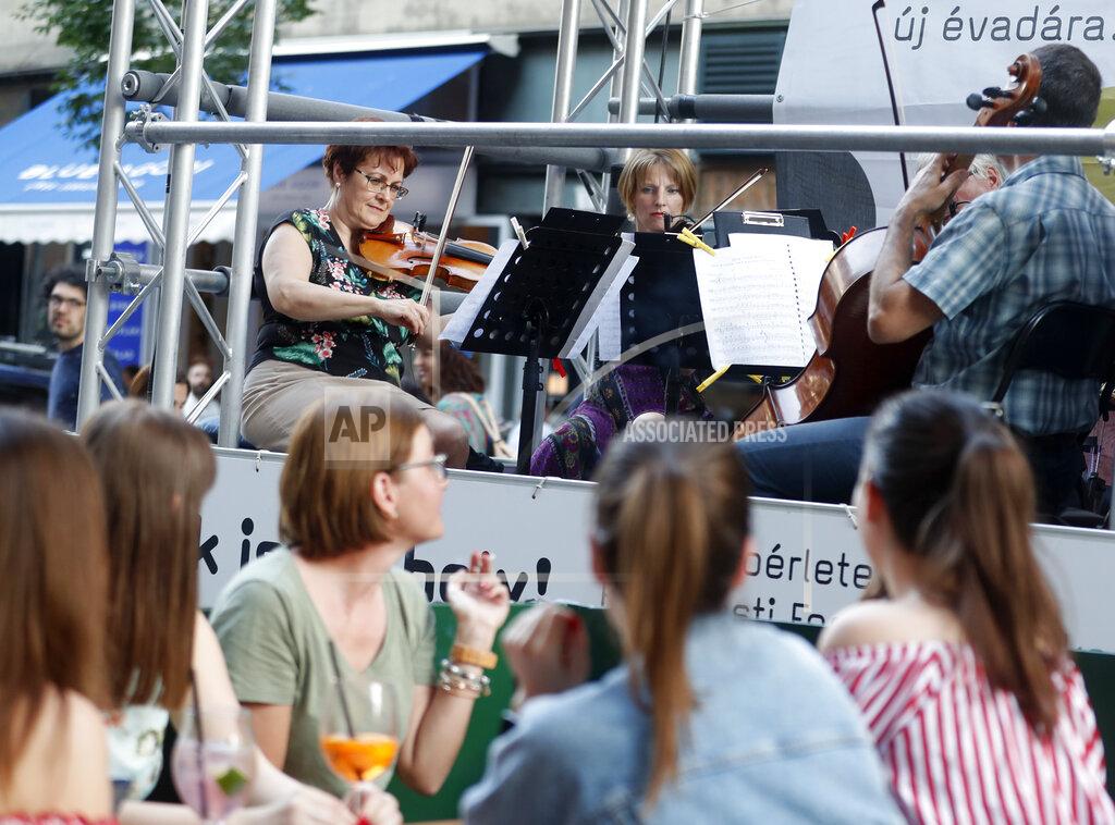 Laszlo Balogh Members of the Budapest Festival Orchestra play music on the back of a truck while driving through downtown Budapest, Hungary, Wednesday June 9, 2021. The prestigious orchestra, founded and led by renowned composer Ivan Fischer, took to the streets as five members of the orchestra performed classical music to motorists and passers-by. The musical parade was aimed at encouraging Hungarians to start returning to live performances in concert halls as the pandemic wanes, after more than a year in which people were homebound and forced to take in their culture online. (AP Photo/Laszlo Balogh)