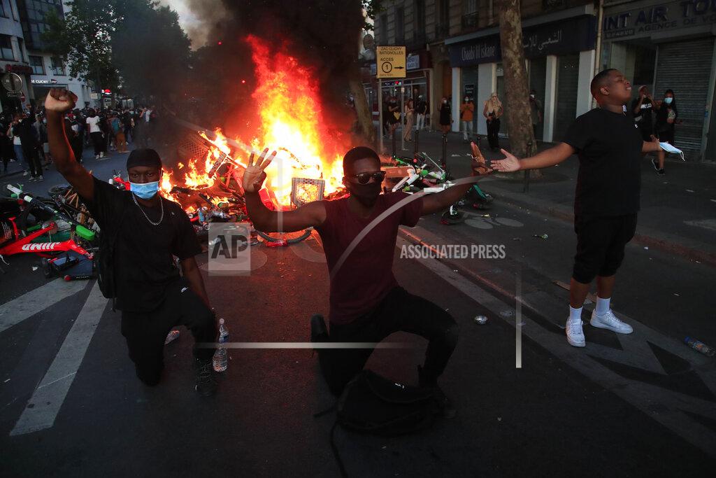 Michel Euler Protesters kneel and react by a burning barricade during a demonstration Tuesday, June 2, 2020 in Paris. Paris riot officers fired tear gas as scattered protesters threw projectiles and set fires at an unauthorized demonstration against police violence and racial injustice. Several thousand people rallied peacefully for two hours around the main Paris courthouse in homage to George Floyd and to Adama Traore, a French black man who died in police custody. (AP Photo/Michel Euler)