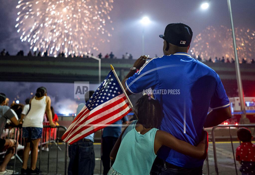 Craig Ruttle FILE - In this July 4, 2018 file photo, Deon Stewart and his daughter Semiyah, of New York, join other spectators as they watch a fireworks display on the east side of Manhattan, part of Independence Day festivities in New York. The Macy's Fourth of July fireworks show will return to New York City this year. (AP Photo/Craig Ruttle, File)