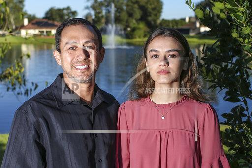 Portrait of Mitch Arbelaez and his daughter Jayden in Jacksonville, Fla., Wednesday, Oct. 13, 2021. Banned from the Florida hospital room where her mother lay dying of COVID-19, Jayden Arbelaez pitched an idea to construction employees working nearby. The workers gave the 17-year-old a yellow vest, boots, a helmet and a ladder to climb onto a section of roof so she could look through the window and see her mother, Michelle Arbelaez, alive one last time. (AP Photo/Gary McCullough)