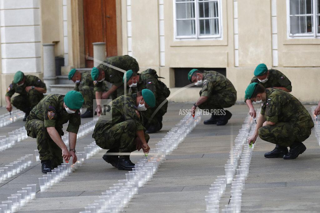 Petr David Josek Soldiers light up candles to commemorate victims of the COVD-19 pandemic at the Prague Castle in Prague, Czech Republic, Monday, May 10, 2021. The Czech Republic is massively relaxing its coronavirus restrictions as the hard-hit nation pays respect to nearly 30,000 dead. (AP Photo/Petr David Josek)