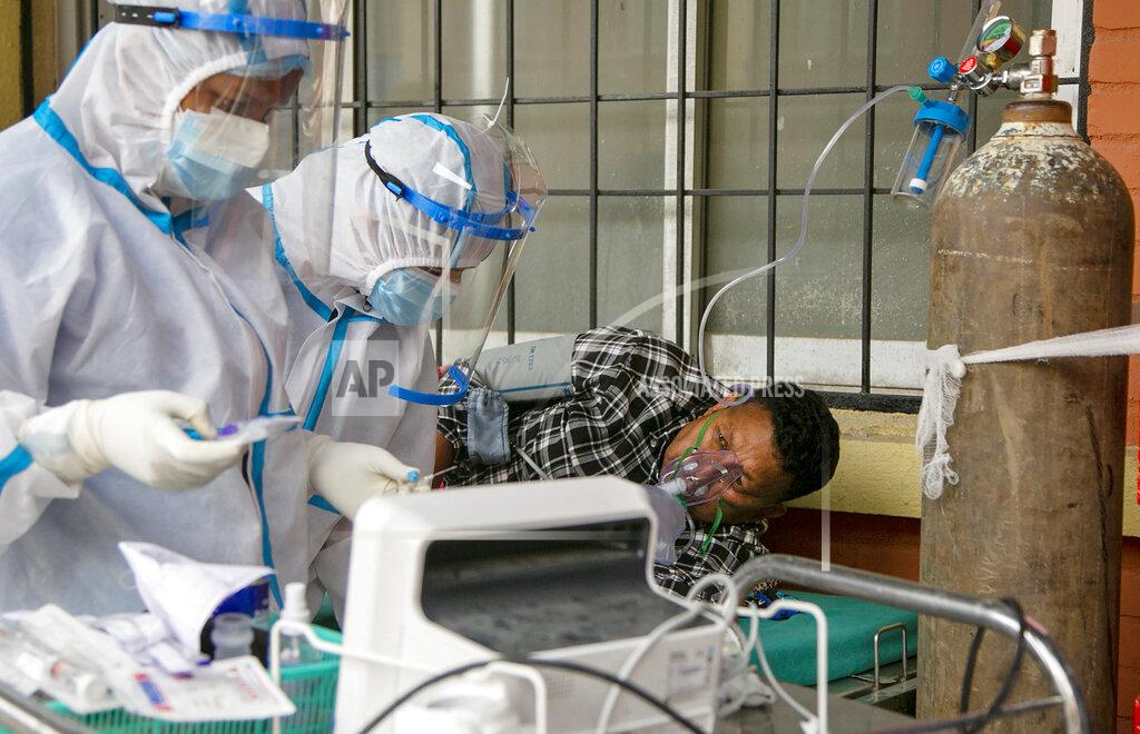 Niranjan Shrestha Nepalese paramedics treat a COVID-19 patient outside an emergency ward of a government run hospital in Kathmandu, Nepal, Friday, May 7, 2021. Across the border from a devastating surge in India, doctors in Nepal warned Friday of a major crisis as daily coronavirus cases hit a record and hospitals were running out of beds and oxygen. (AP Photo/Niranjan Shrestha)