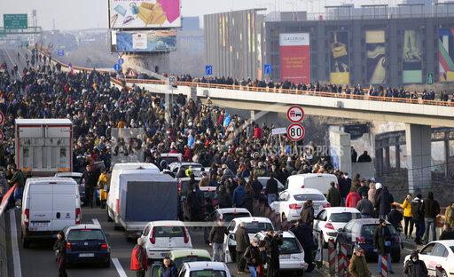 Protesters stand on the highway during a protest in Belgrade, Serbia, Saturday, Dec. 4, 2021. Thousands of protesters have gathered in Belgrade and other Serbian towns and villages to block roads and bridges despite police warnings and an intimidation campaign launched by authorities against the participants. Thousands of protesters have gathered in Belgrade and other Serbian towns and villages to block roads and bridges despite police warnings and an intimidation campaign launched by authorities against the participants. (AP Photo/Darko Vojinovic)