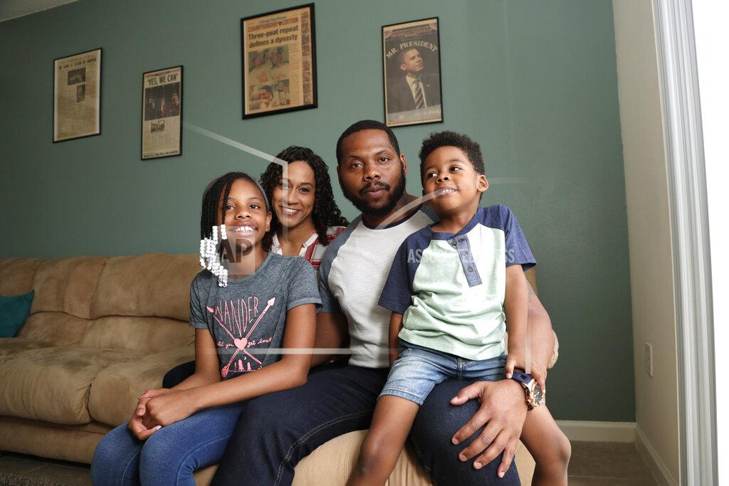 Lynne Sladky In this Tuesday, June 16, 2020 photo, D.J. Boldin, second from right, poses for a photograph with his children Madison, 10, left, and Dallas, 4, right, and his fiancee Sasha Jones at their home in Miramar, Fla. Boldin is the football coach at Pahokee High School, a predominantly black school located alongside Lake Okeechobee in Florida. Recent events have given Boldin an opportunity to use his position to prepare his players for the challenges they will face when they leave the bubble that is their small town. (AP Photo/Lynne Sladky)