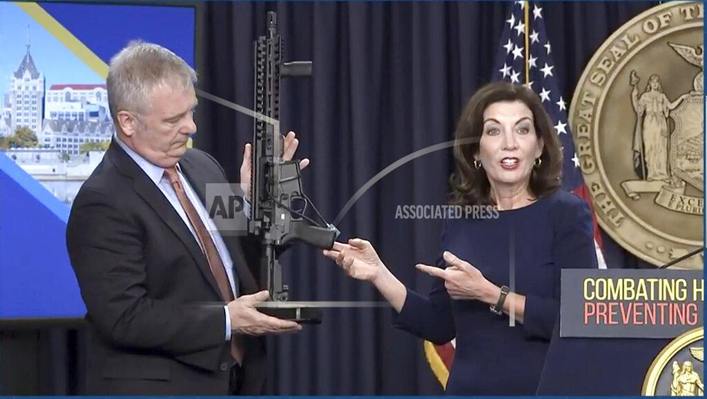 Uncredited In this image taken from video, Kevin Bruen, Superintendent of the New York State Police, holds a firearm as New York Gov. Kathy Hochul speaks during a news conference, Wednesday, May 18, 2022, in New York. New York would require state police to seek court orders to keep guns away from people who might pose a threat to themselves or others under a package of executive orders and gun control bills touted Wednesday by Hochul in the aftermath of a racist attack on a Buffalo supermarket. (Office of the Governor of New York via AP)