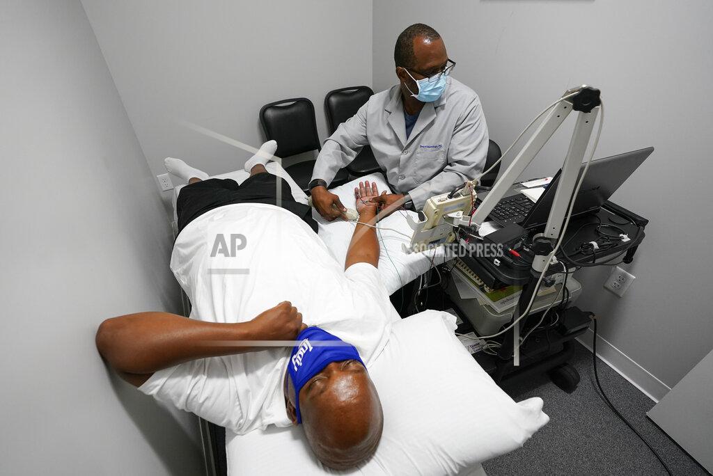 Darron Cummings Larry Brown is tested by Dr. Jerry Smartt, Monday, Aug. 17, 2020, in Carmel, Ind. While hospitalized because of COVID-19 starting in March, doctors moved Brown to the ICU and started him on the ventilator while grappling with how to treat him. They tried the common antibiotic azithromycin, but his pneumonia grew worse. They administered the malaria treatment touted by President Donald Trump, hydroxychloroquine, but saw no progress. They put him in a medically induced coma, and attached him to an ECMO machine, which essentially did the job of his lungs by transferring oxygen into his blood. (AP Photo/Darron Cummings)
