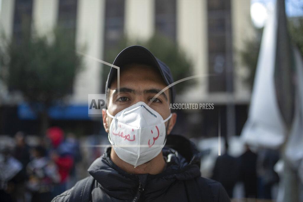 Mosa'ab Elshamy A young man wearing a face mask poses for a portrait during a protest on the tenth anniversary of the uprising that toppled longtime autocrat Ben Ali, during to a national lockdown after a surge in COVID-19 cases, in Tunis, Thursday, Jan. 14, 2021. Writing in Arabic on facemark reads "We will not be silenced." Tunisia is commemorating the 10th anniversary since the flight into exile of its iron-fisted leader, Zine El Abidine Ben Ali, pushed from power in a popular revolt that foreshadowed the so-called Arab Spring. But there will be no festive celebrations Thursday marking the revolution in this North African nation, ordered into lockdown to contain the coronavirus. (AP Photo/Mosa'ab Elshamy)
