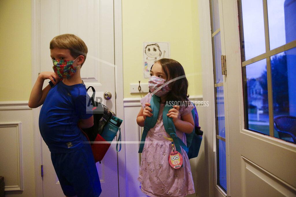 Brynn Anderson Siblings Paul Adamus, 7, left, and Neva Adamus, 5, put on their backpacks to get ready for their first day of school on Monday, Aug. 3, 2020, in Dallas, Ga. Neighboring states arrived at differing conclusions on who’s in charge of the reopening of schools. The differences in philosophy underscore some of the difficulties facing states as they grapple with how to proceed amid growing coronavirus infections in numerous states. (AP Photo/Brynn Anderson)