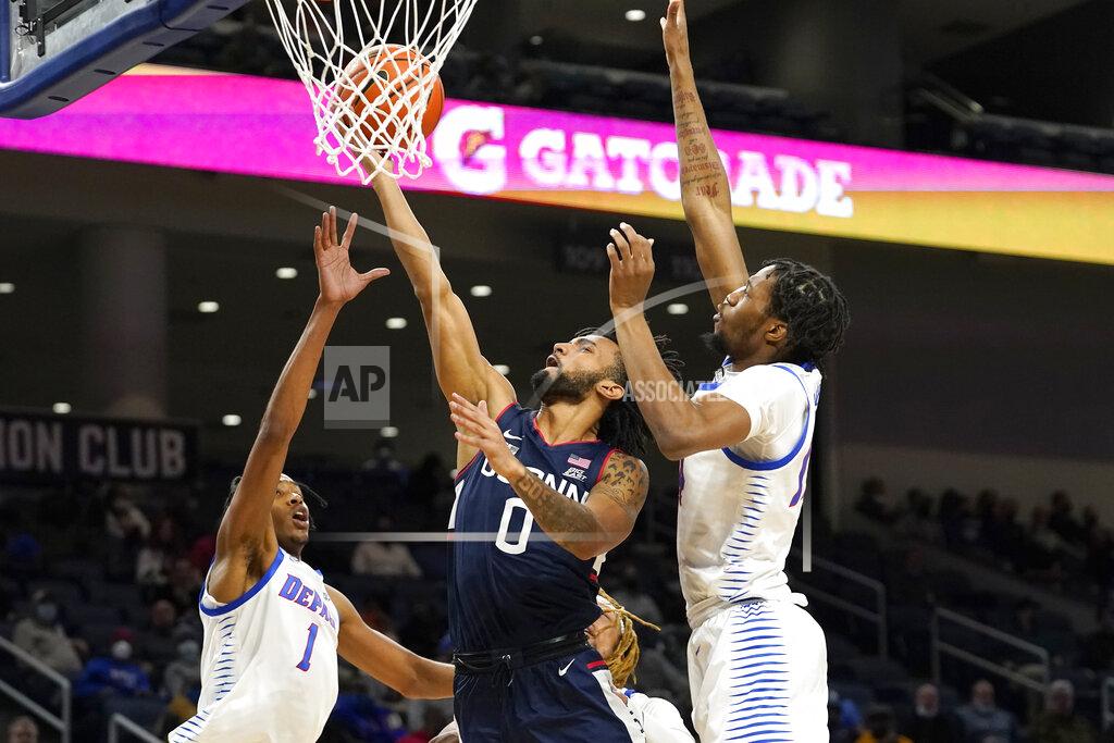 Charles Rex Arbogast Connecticut's Jalen Gaffney (0) shoots between DePaul's Javan Johnson (1) and Nick Ongenda during the first half of an NCAA college basketball game Saturday, Jan. 29, 2022, in Chicago. (AP Photo/Charles Rex Arbogast)