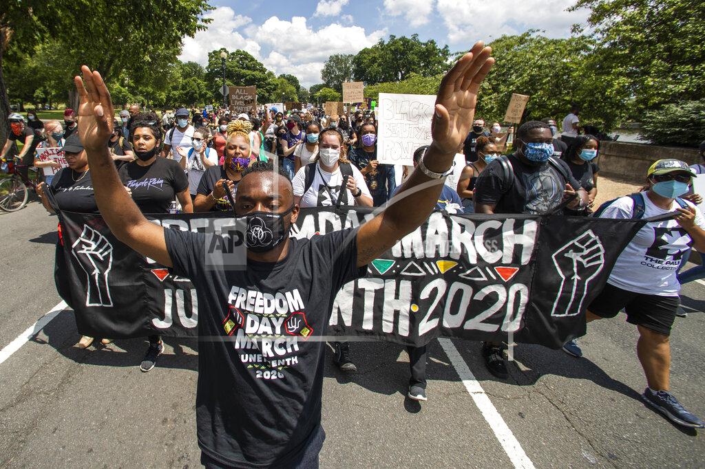 Malik Harris, left, leads protesters as they march towards the Martin Luther King Jr. Memorial in Washington on Friday, June 19, 2020, to mark Juneteenth, the holiday celebrating the day in 1865 that enslaved black people in Galveston, Texas, learned they had been freed from bondage, more than two years after the Emancipation Proclamation. (AP Photo/Manuel Balce Ceneta)