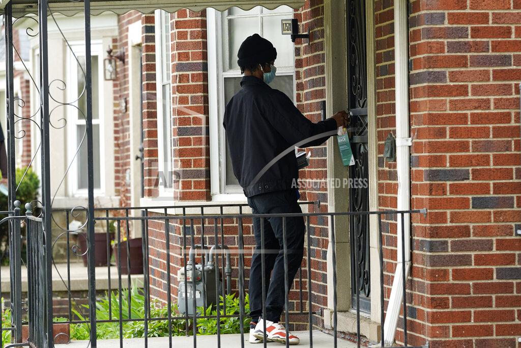 Paul Sancya Deares Carey leaves a flyer on a home in Detroit, Tuesday, May 4, 2021. Officials are walking door-to-door to encourage residents of the majority Black city to get vaccinated against COVID-19 as the city's immunization rate lags well behind the rest of Michigan and the United States. (AP Photo/Paul Sancya)