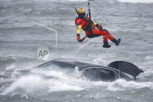 U.S. Coast Guard rescue swimmer Petty Officer 2nd Class Derrian Duryea is lowered from a hovering helicopter to pull a body from a submerged vehicle stuck in rushing rapids just yards from the brink of Niagara Falls, Wednesday, Dec. 8, 2021, in Niagara Falls, N.Y. (AP Photo/ Jeffrey T. Barnes)
