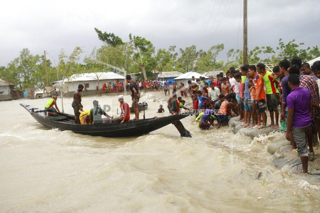 Abu Sufian Jewel In this Wednesday, May 20, 2020 photo, a boat brings people to land, as locals check an embankment before Cyclone Amphan made landfall, in Shyamnagar, Shatkhira, Bangladesh. A powerful cyclone that slammed into coastal India and Bangladesh has left damage difficult to assess Thursday. (AP Photo/Abu Sufian Jewel)