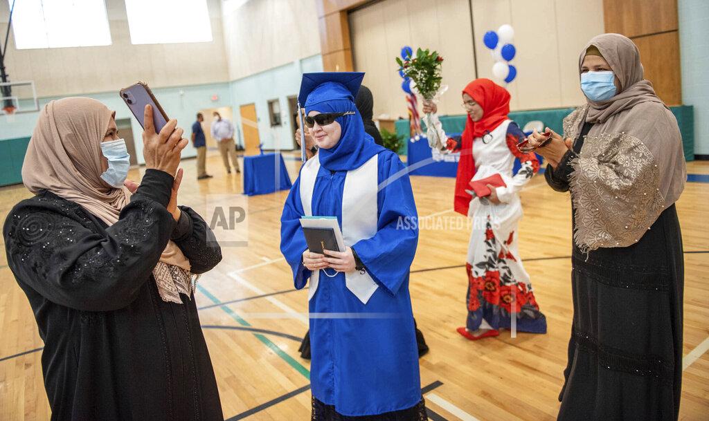 Andree Kehn Melak Jashaami, center, is surrounded by family and friends dancing and clapping in a traditional Arabic celebration honoring Jashaami's graduation on Wednesday, Aug. 12, 2020 from Lewiston High School. The single person ceremonies happened at hour intervals through the day at Connors Elementary School in Lewiston to keep participants safer from the risk of COVID-19 transmission. (Andree Kehn/Sun Journal via AP)