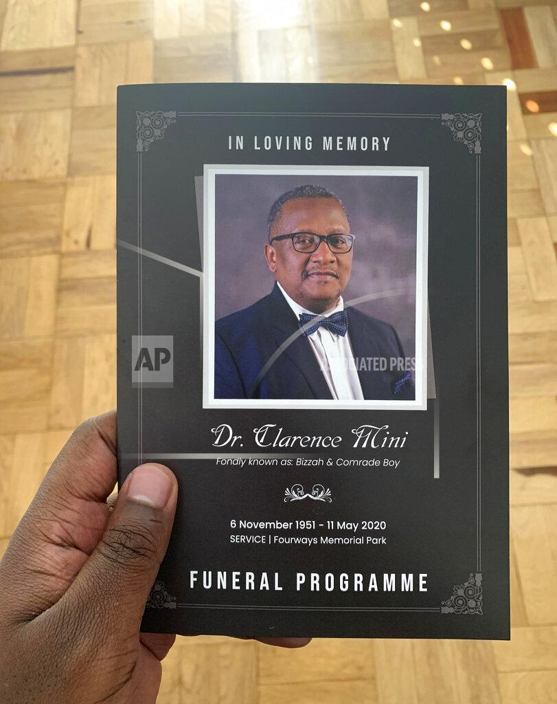 Yandi Mini This Wednesday, June 10, 2020 photo provided by Yandi Mini shows him holding the funeral programme of his father, Dr. Clarence Mini at his Johannesburg home. Clarence Mini, a South African activist and doctor who died of COVID-19 spent his life fighting apartheid, the government's denial of HIV/AIDS and rampant corruption. Loved ones say Mini knew the odds were against him but he was committed to what he believed was right. He died in May at age 69. (Yandi Mini via AP)