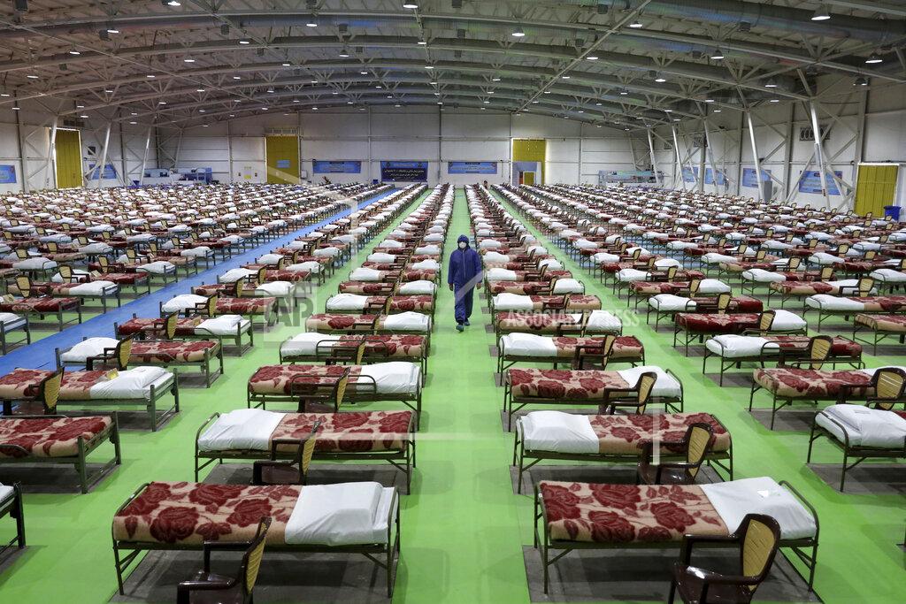 Ebrahim Noroozi A member of the Iranian army walks past rows of beds at a temporary 2,000-bed hospital for coronavirus patients set up by the army at the international exhibition center in northern Tehran, Iran, on March 26, 2020. (AP Photo/Ebrahim Noroozi, File)