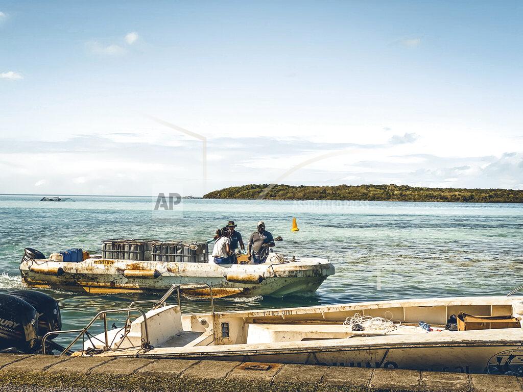 Uncredited In this photo provided by Grégoire Rouxel people on a boat evaluate damage from fuel leaking from a ship off shore that ran aground in the ocean, Friday, Aug. 7, 2020, in Mauritius. The Indian Ocean island of Mauritius has declared a "state of environmental emergency" after a Japanese-owned ship that ran aground offshore days ago began spilling tons of fuel. Prime Minister Pravind Jugnauth announced the development late Friday, Aug. 7, as satellite images showed a dark slick spreading near environmental areas the government called "very sensitive." (@gregrouxel via AP)