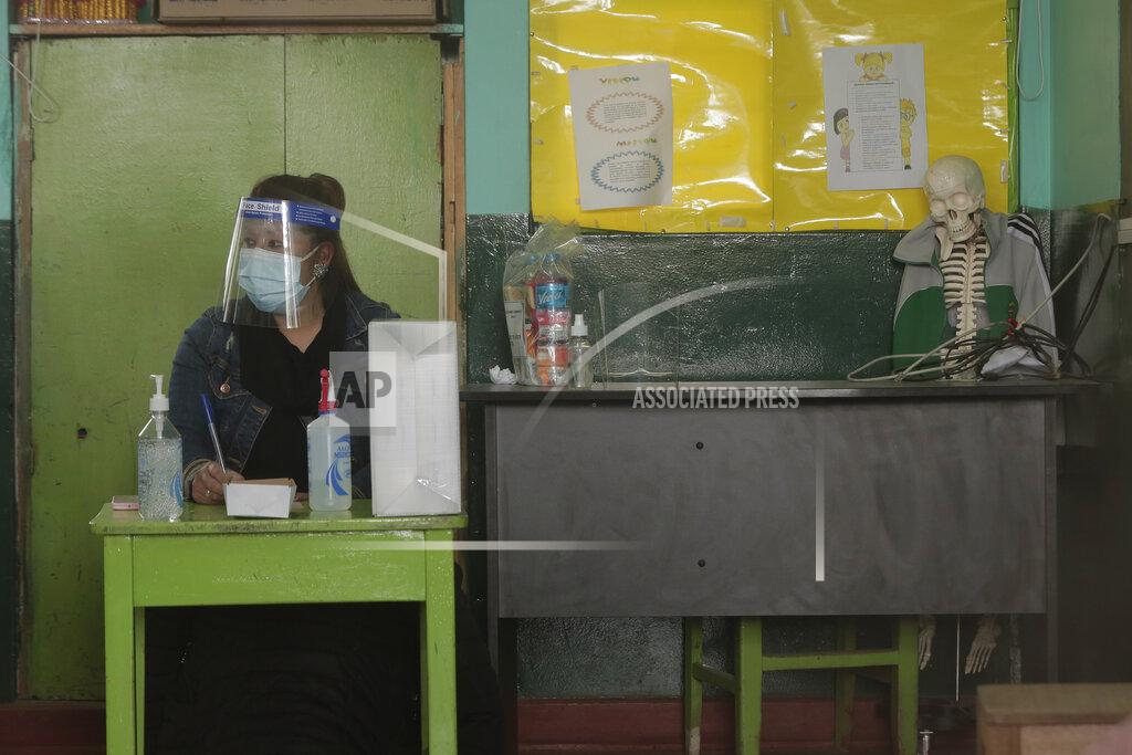 Sharon Castellanos Wearing a mask and face shield, an electoral official waits for voters at a school being used as a polling station during general elections in Cuzco, Peru, Sunday, April 11, 2021. Peruvians went to the polls amid a surge in new COVID-19 infections. (AP Photo/Sharon Castellanos)