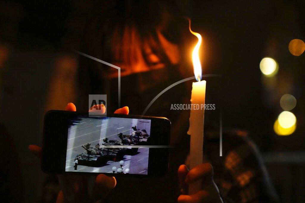 Kin Cheung People light candle to mark the anniversary of the military crackdown on a pro-democracy student movement in Beijing, outside Victoria Park in Hong Kong, Friday, June 4, 2021. A member of the committee that organizes Hong Kong's annual candlelight vigil for the victims of the Tiananmen Square crackdown was arrested early Friday on the 32nd anniversary. (AP Photo/Kin Cheung)