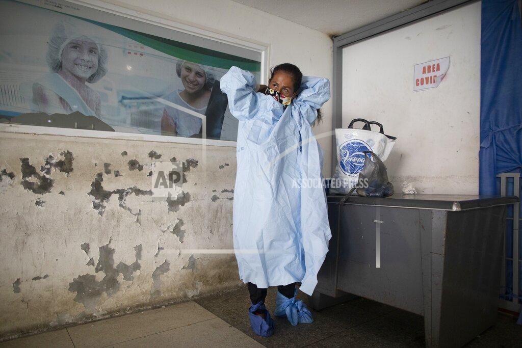 Ariana Cubillos Elena Suazo, a kindergarten cafeteria worker, puts on the protective gear she brought from home, outside the entrance to the COVID-19 wing of José Gregorio Hernández Hospital which used to be the emergency room, as she prepares to enter and care for her 76-year-old hospitalized father, in the Catia neighborhood of Caracas, Venezuela, Thursday, Sept. 24, 2020. In this ruined country, the only way to ensure that he received the care he needed was to do it herself, regardless of the dangers to her own health. (AP Photo/Ariana Cubillos)