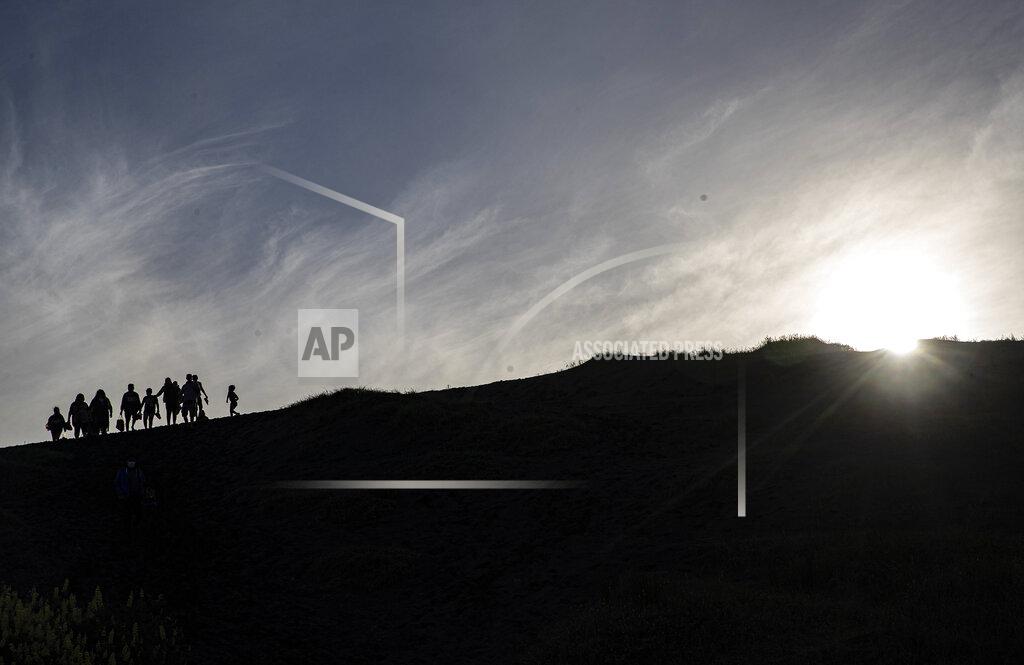 Esteban Felix People walk on a dune, a day before a total eclipse in Nahuelpan, La Araucania, Chile,Sunday, Dec. 13, 2020. The total eclipse will be visible from Chile and the northern Patagonia region of Argentina, and as a partial solar eclipse in Bolivia, Brazil, Ecuador, Paraguay, Peru and Uruguay. (AP Photo/Esteban Felix)